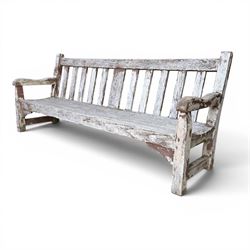 Teak garden bench with slatted back and seat on square supports in weathered which finish 