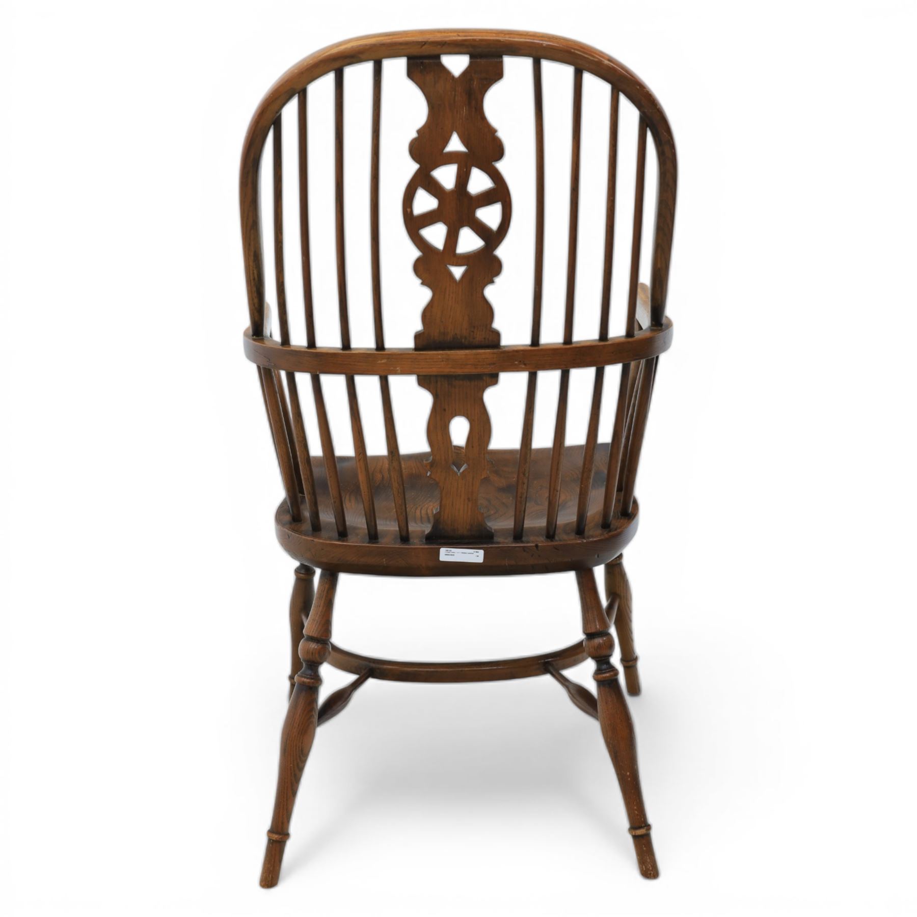 Late 19th century stained elm and beech Windsor armchair, the arched hoop back with pierced wheel splat above shaped lower splat between turned spindles, shaped arm rail on turned supports, saddle seat, raised on turned legs united by a crinoline stretcher