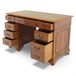 Late 20th century yew wood nine drawer writing desk, rectangular top inset with gilt-tooled green leather, above an arrangement of nine drawers with brass swan-neck handles, raised on bracket feet