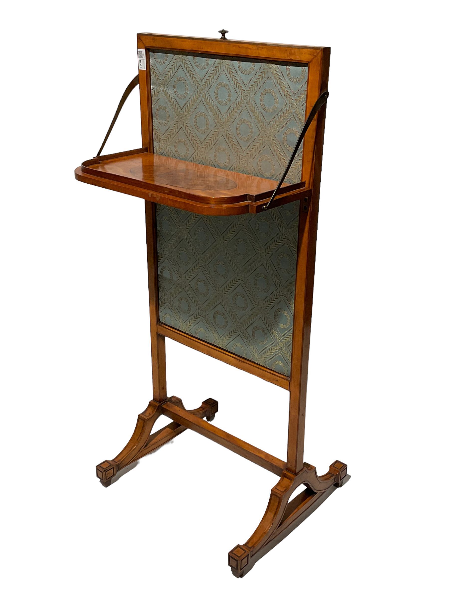 Late George III satinwood fire screen, upholstered in floral blue fabric, fold-down lipped tray with central figured walnut oval inlay, on splayed supports joined by stretchers 