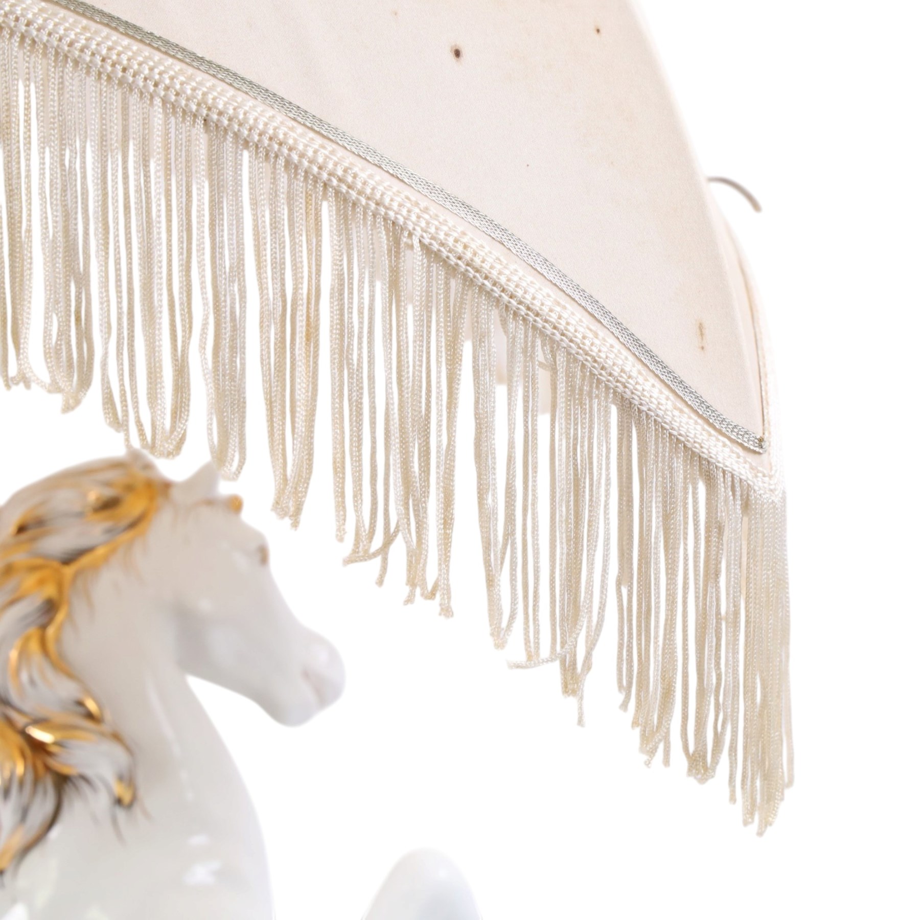 Italian-style ceramic table-lamp featuring two white running horses with gold accents, with cream tasselled lampshade, upon a wooden base, approx. H60cm W40cm