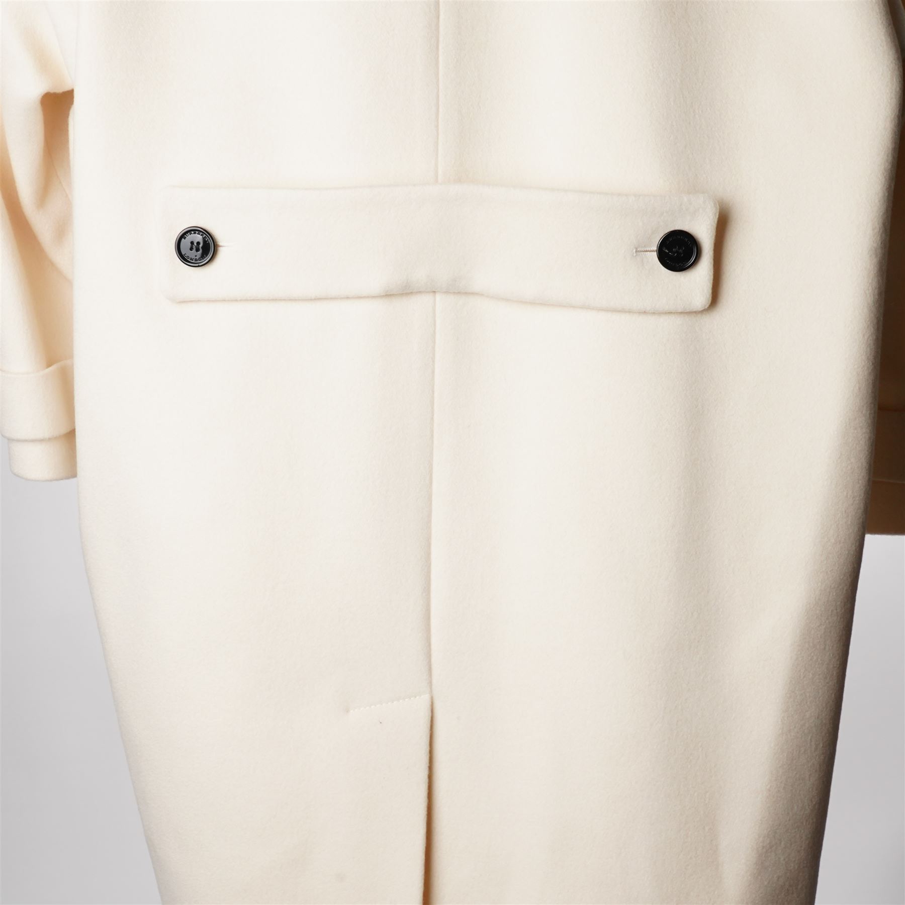 Burberry London - wool coat in cream, with concealed front popper fastening, bracelet-length sleeves with tab and black button detail and side slip pockets, with slit to back, size 40, unused with original Harvey Nichols garment bag and hanger