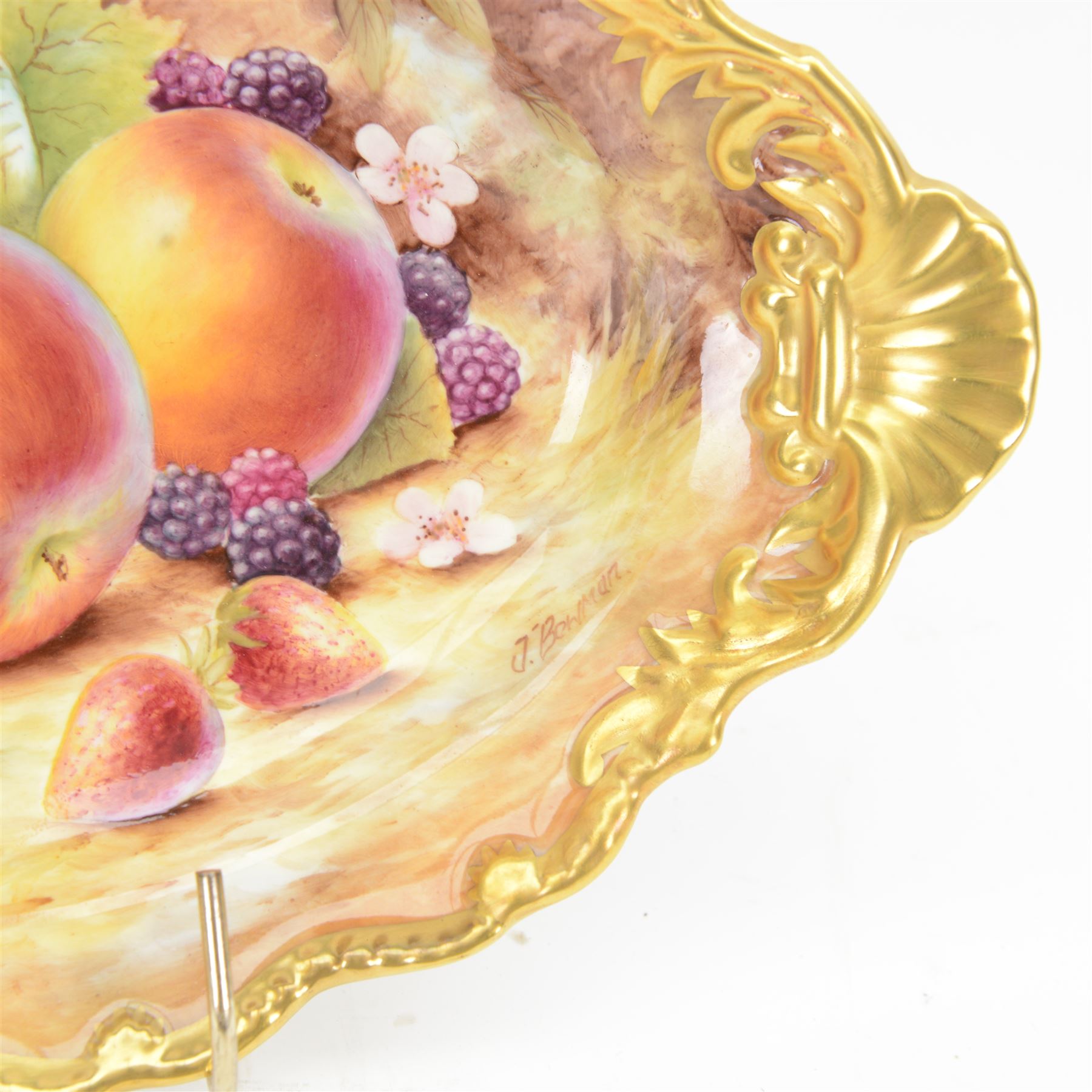 Late 20th century Royal Worcester dish, of oval form with gilt shaped rim and twin shell handles, hand painted by Jason Bowman with still life of fruit upon mossy ground, signed J Bowman, wit marks beneath, with makers fitted card box


