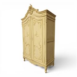 French Louis XV design cream painted double armoire, serpentine moulded pediment surmounted by carved foliate crest, enclosed by two shaped panel doors with applied scroll and leaf mouldings, enclosing a hanging rail and adjustable shelving, fluted uprights with carved floral terminals, on shaped apron and cabriole feet
