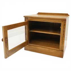 Ercol - elm media cabinet of small proportions, fitted with glazed door enclosing single shelf, on skirted base