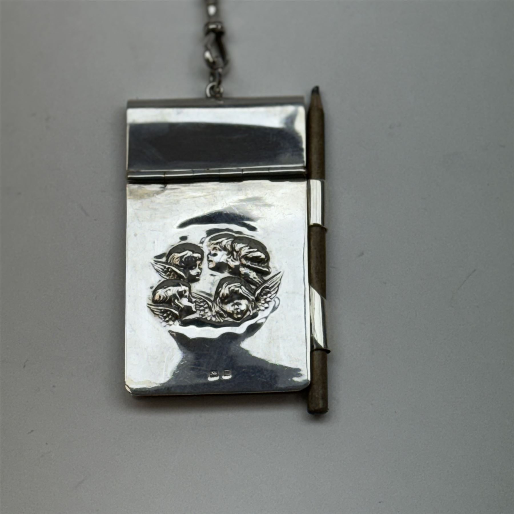 Victorian and later silver chatelaine, the shaped and foliate pierced clasp with embossed oval panel of a courting couple, hallmarked Levi & Salaman, Birmingham 1899, supporting six accessories on five chains: a circular mirror embossed with putti, hallmarked Henry Matthews, Birmingham 1911, pencil holder engraved with foliate scrolls, hallmarked Francis Webb, Birmingham 1914, conical scent bottle decorated with bamboo, (unmarked but testing as silver), aide memoire embossed with putti, hallmarked Samuel M Levi, Birmingham 1911, tape measure of compressed spherical form, hallmarked Henry Matthews, Birmingham 1899, and a purse with embossed putti, hallmarked Birmingham 1909, makers mark worn and indistinct, at longest point L31cm

