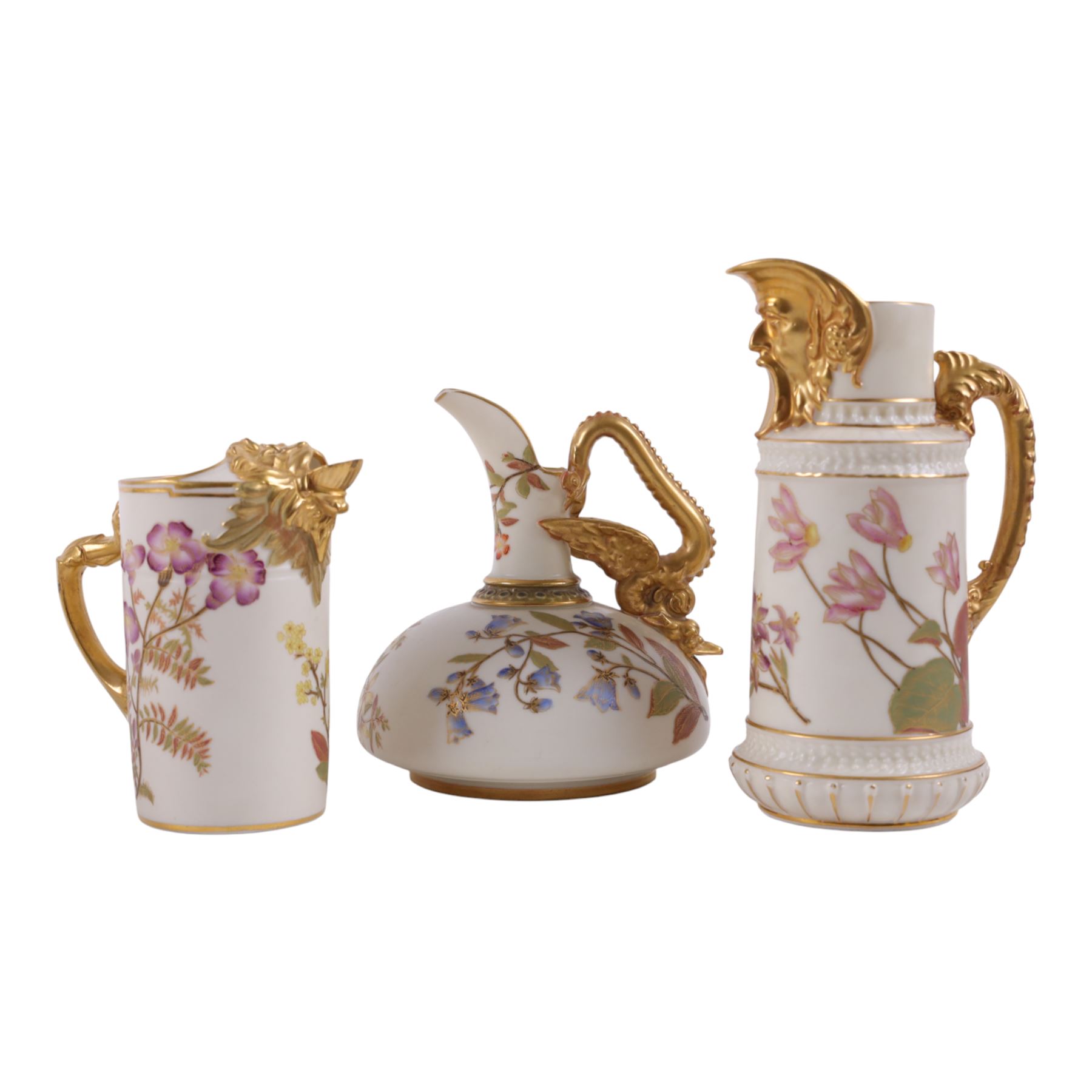 Three Royal Worcester jug in Blush Ivory, comprising squat winged dragon handled jug shape 1048, lion mask jug shape 1258 and Bacchus mask jug shape 1366, all with puce mark to base 