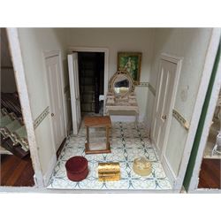 Two modern three storey dolls houses, each painted green with decorated interiors, both upon a single white wooden base, together with a large collection of dolls house furniture, accessories and figures 