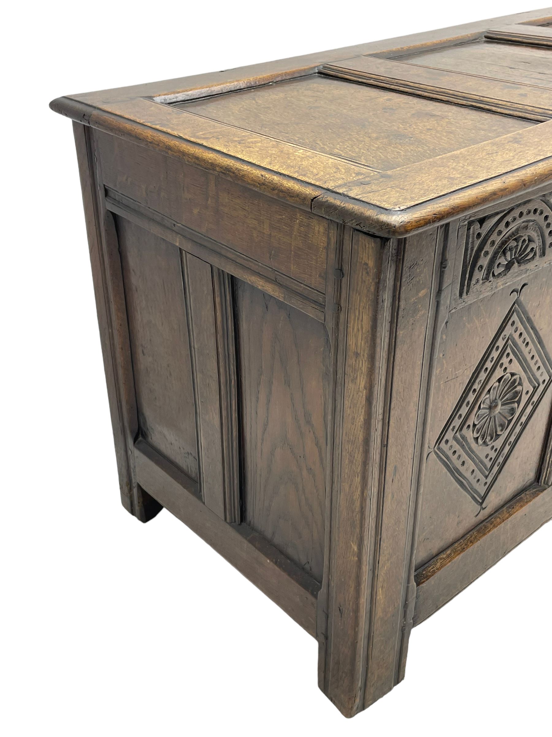 18th century oak coffer or chest, rectangular triple panelled hinged top with moulded edge enclosing main compartment and candle box, the frieze carved with repeating concentric lunettes and foliate patterns, the front fielded panels decorated with lozenges containing central flower heads, on stile supports