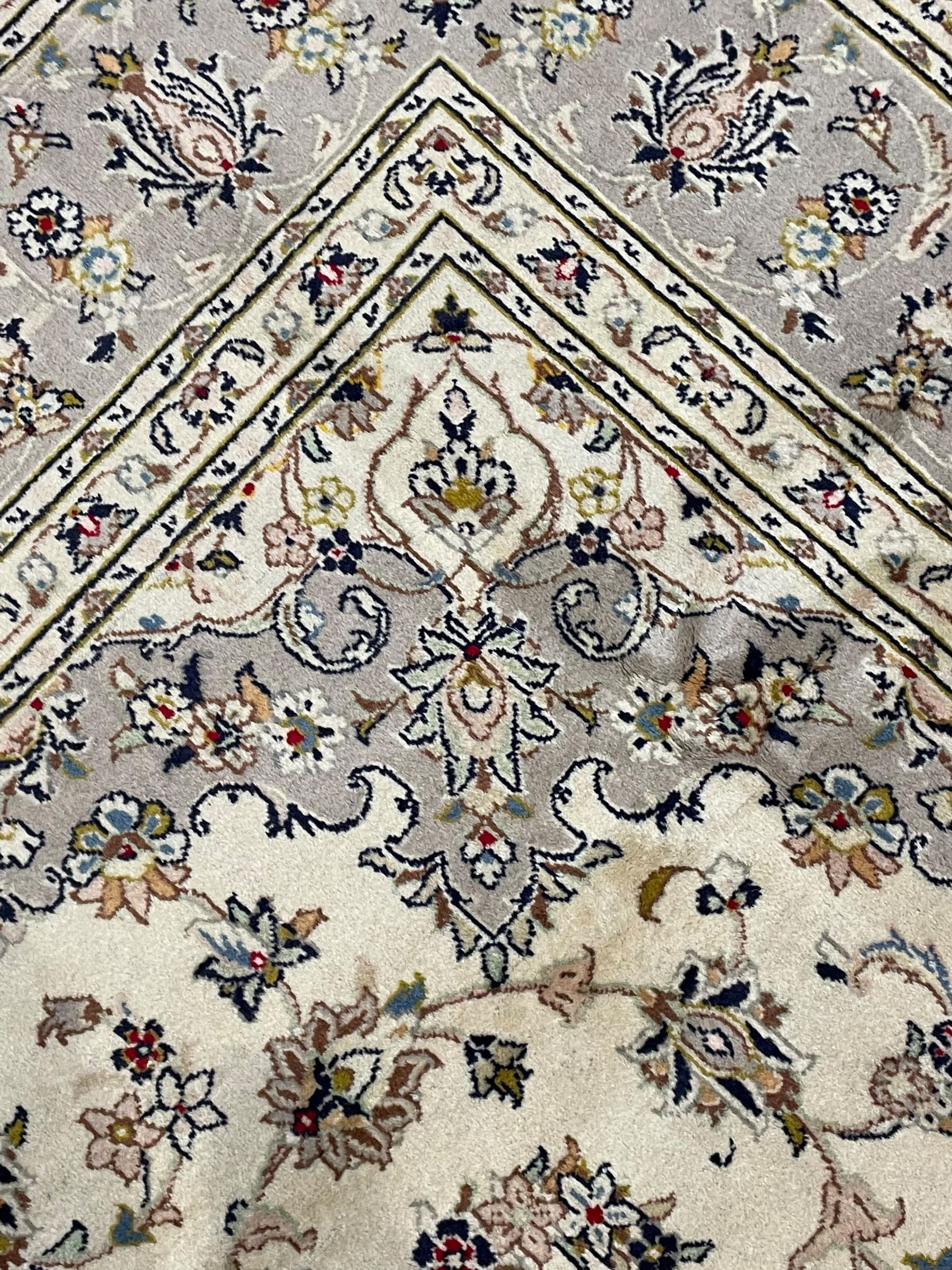 Persian Kashan ivory ground carpet, floral central medallion surrounded by trailing leafy branches and palmettes, floral pattern spandrels and matching border, within guard stripes