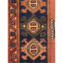 Late 20th century Afghan style ground runner, woven with a repeating panel design along a terracotta field and indigo grounds, framed by multiple narrow borders, and finished with fringed ends