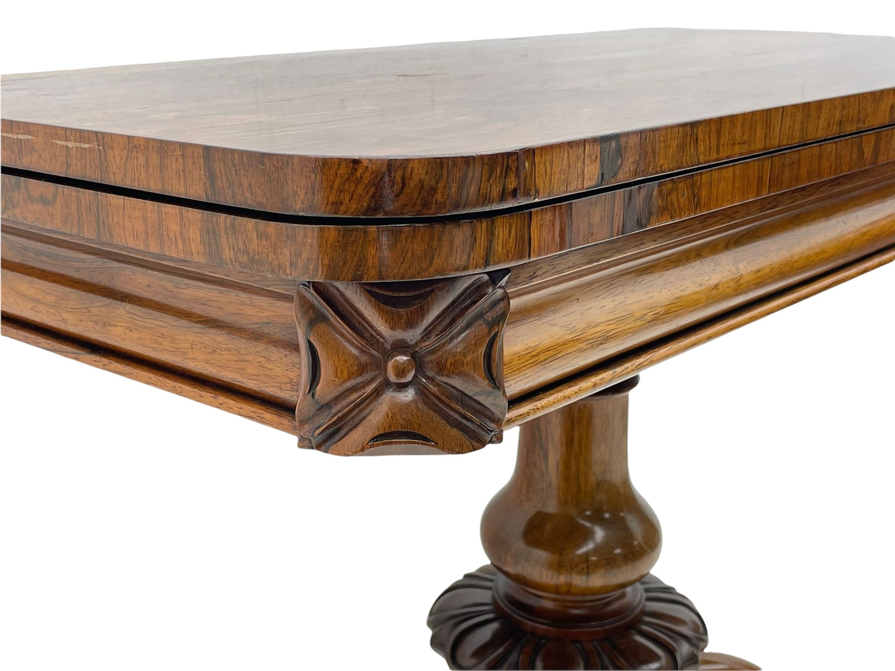 Victorian figured rosewood card table, fold-over swivel top with circular baize lining, moulded frieze with stylised flower head carving to corners, turned column with egg and dart decoration, on quadruple splayed c-scroll carved supports, with brass castors