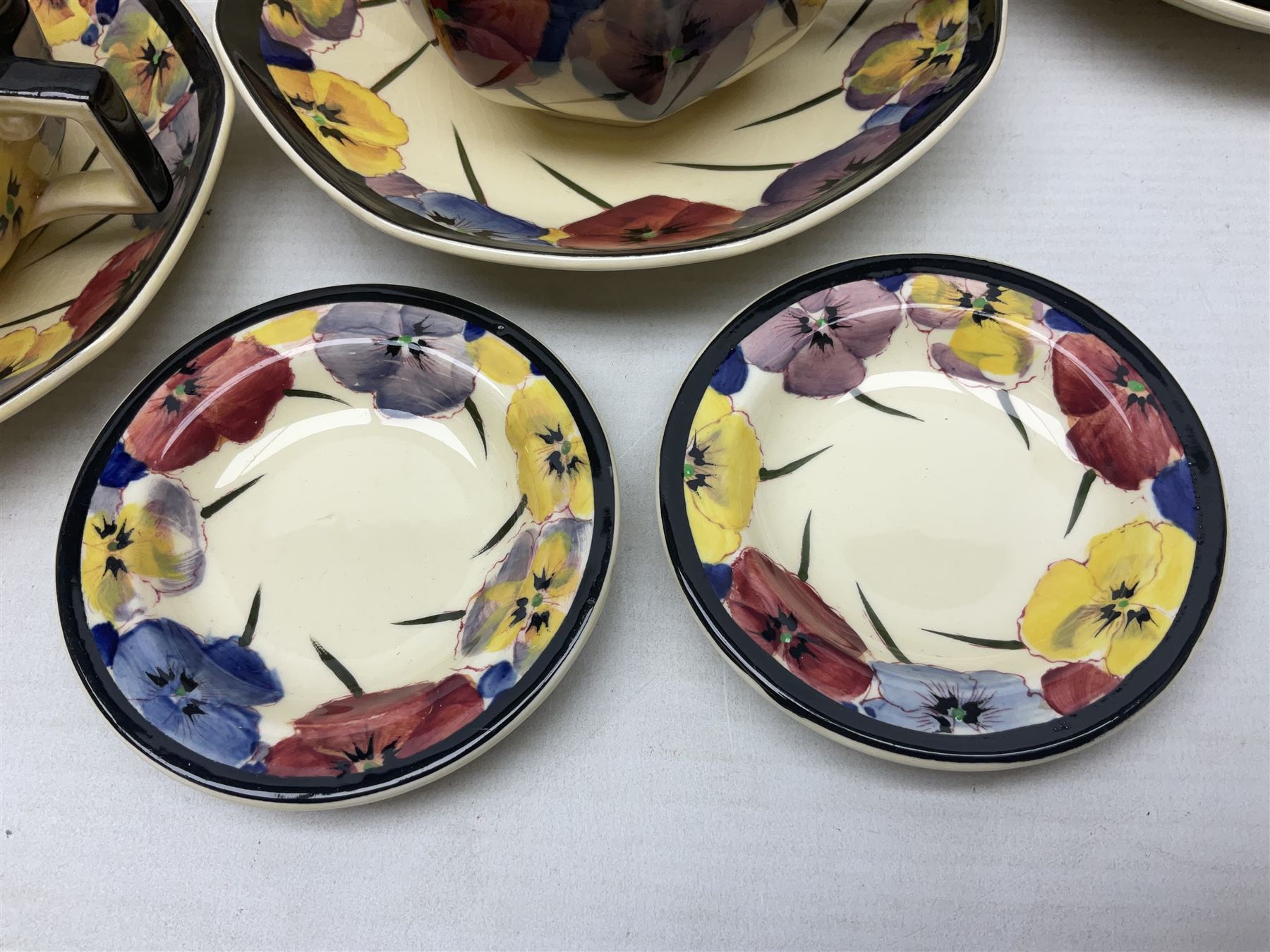 Early 20th century Art Deco Royal Doulton Pansies pattern octagonal teawares, comprising three larger teacups and saucers, three smaller teacups and saucers, open sucrier, two jugs, slop bowl, six side plates, two larger plates, two small circular dishes and one long twin handled rectangular dish, all with printed marks beneath, Rd No 597783, pattern no D4049