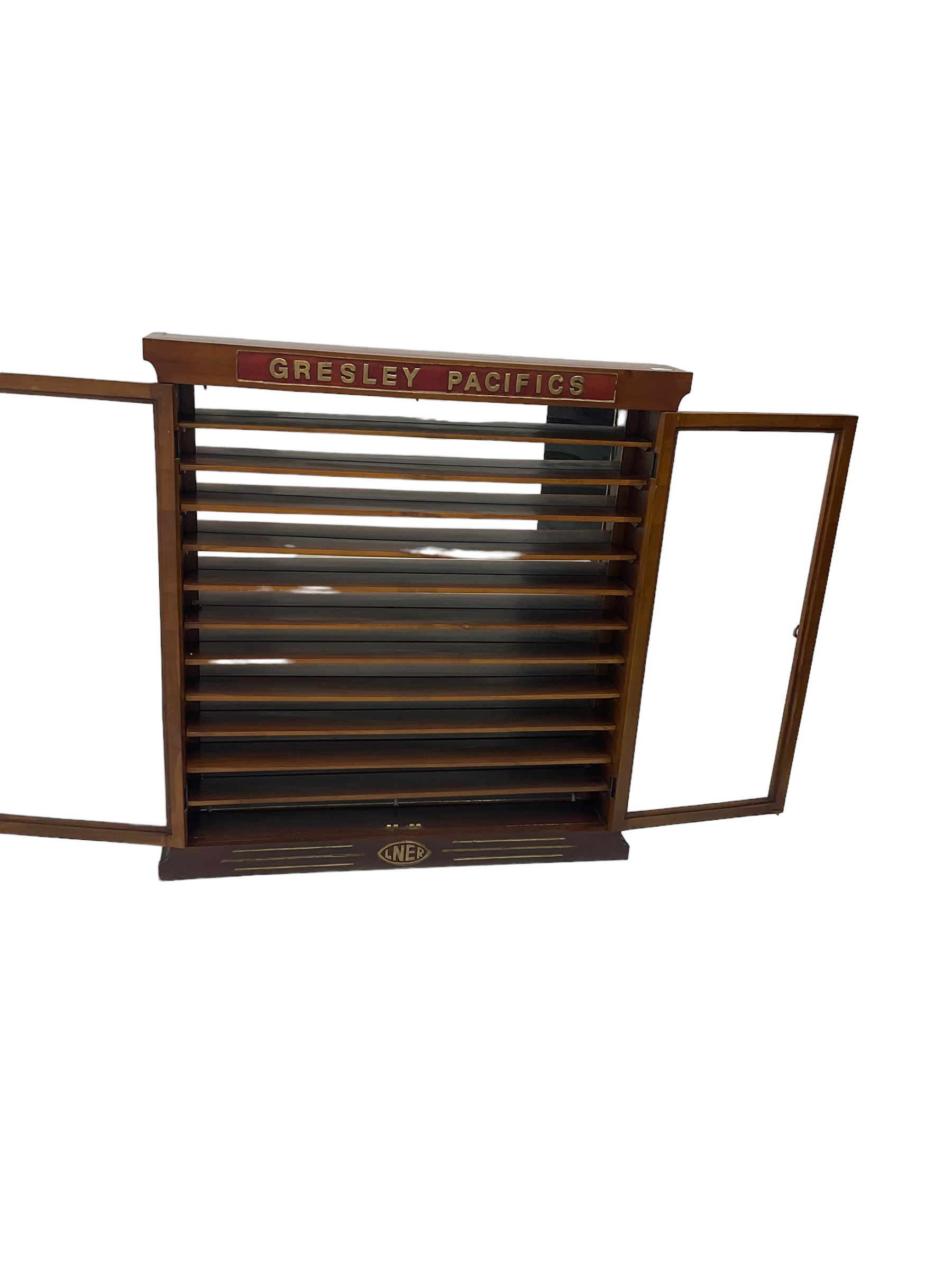 Modern hardwood display cabinet for model railway locomotives inscribed 'Gresley Pacifics' to the frieze and 'LNER' to the bottom rail; with mirrored back and ten loose fitting shelves enclosed by a pair of unglazed doors L101cm H108cm D16cm