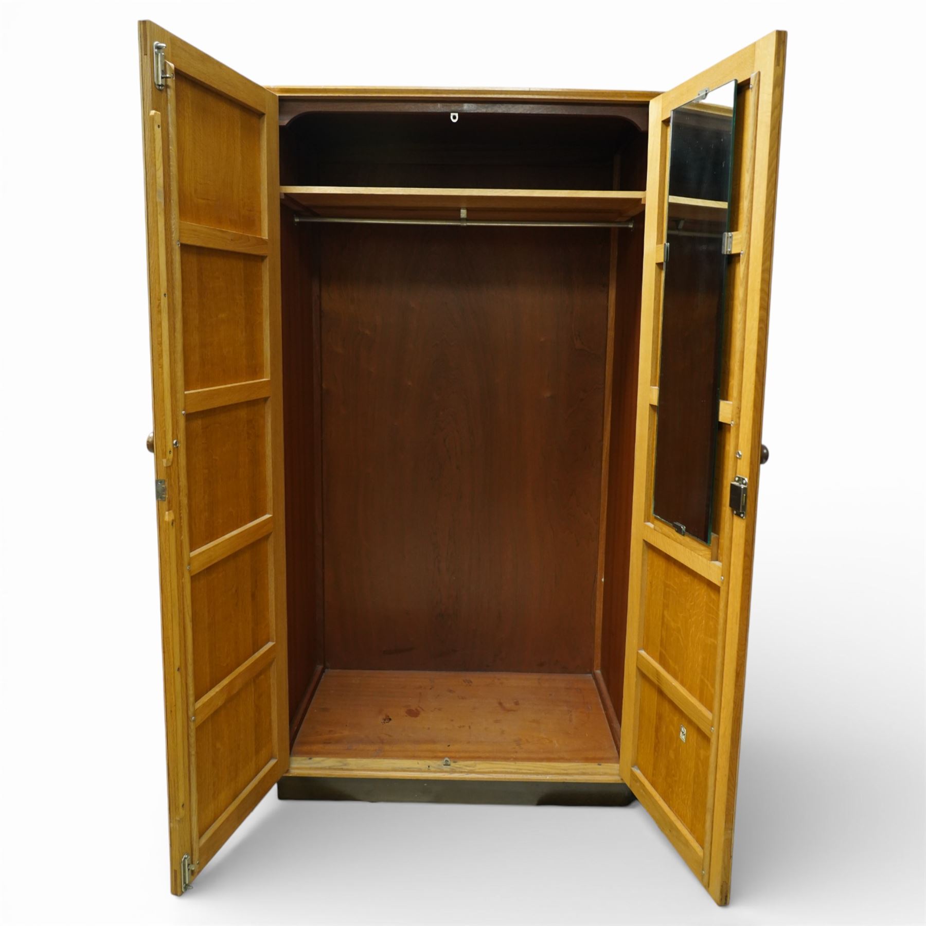 Mid 20th century oak veneered wardrobe, the plain rectangular top above a pair of hinged doors fitted with circular handles, opening to reveal a hanging rail and upper shelf, one door with inset mirror, the whole raised on a plinth base