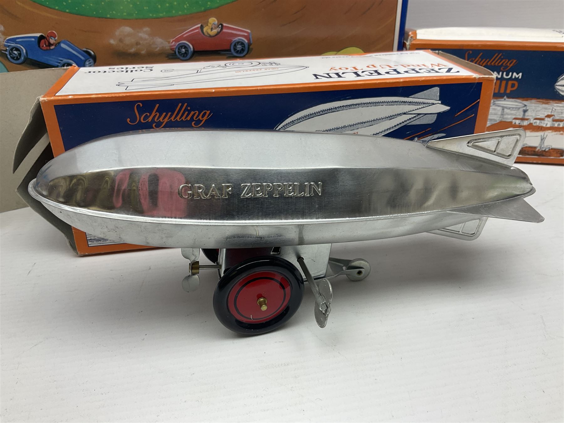 Schylling - six tinplate models comprising Sir Ian’s Bluebird racing car, Speedway Auto Racer, two Aluminium Airships, Tin Speedboat and Ernest in the Music Box; all in original boxes 