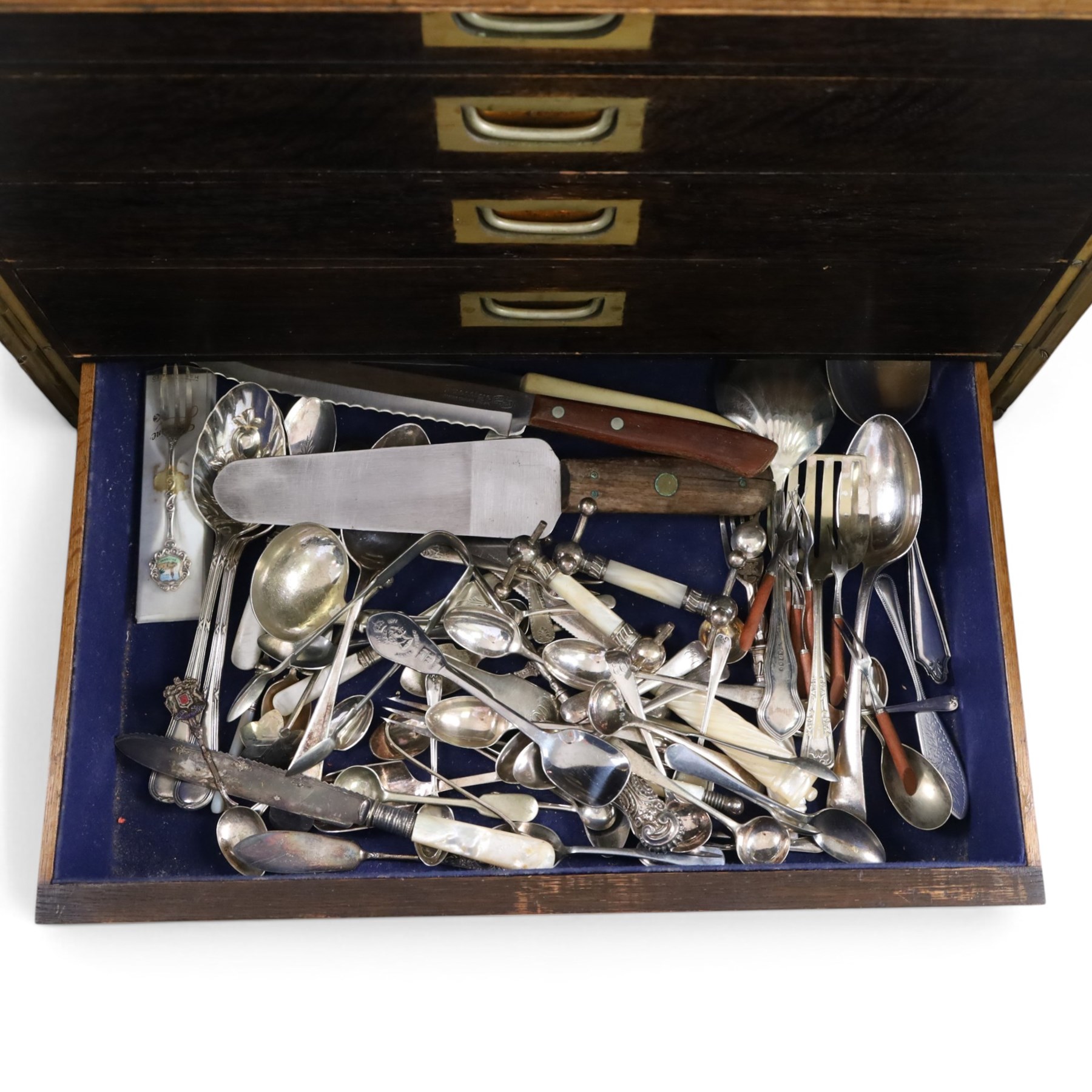 Ealy 20th century oak canteen, with five drawers behind double doors, four drawers containing a part set of silver plated Hanoverian pattern cutlery with engraved monograms and a set of twelve mother of pearl handled fruit knives and forks, the last drawer containing a collection of loose silver plated cutlery, canteen H39cm, W48cm