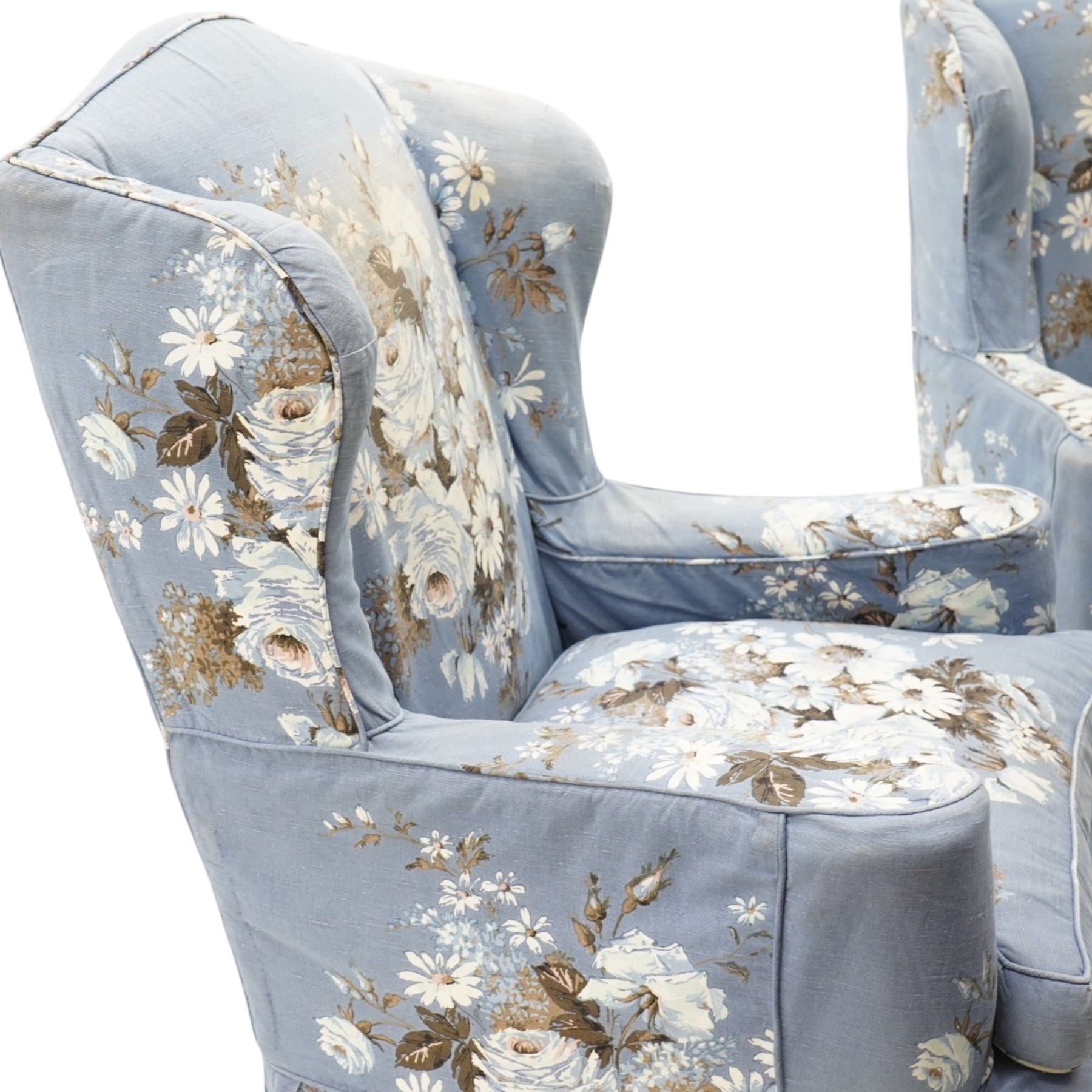 Pair of Queen Anne wingback armchairs, high back over out-swept arms, raised on ball-and-claw feet, upholstered in sky-blue ground floral chintz loose upholstery with pleated skirt and squab cushion