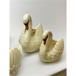 Four Dartmouth pottery jardinières or planters, modelled in the form of swans, comprising three white examples, and one black, marked beneath Dartmouth Devon England, larger examples H29cm, smaller examples H21.5cm. 