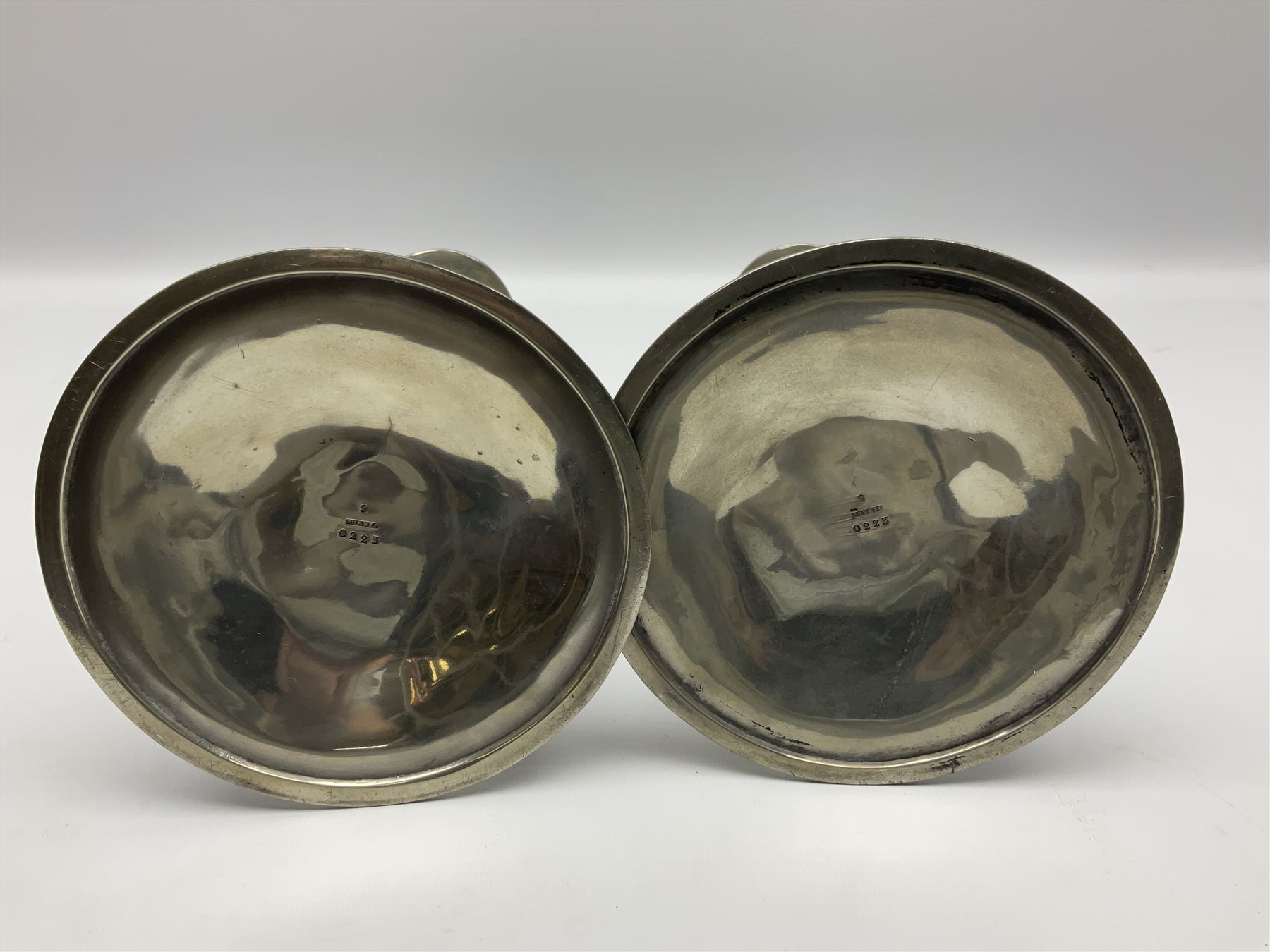 Archibald Knox (1864-1933) for Liberty & Co, pair of Tudric pewter candlesticks, the bud shaped sockets raised upon three angular fin supports and a slightly domed circular base with cast stylised foliate decoration, each stamped beneath Tudric 0223, H30cm