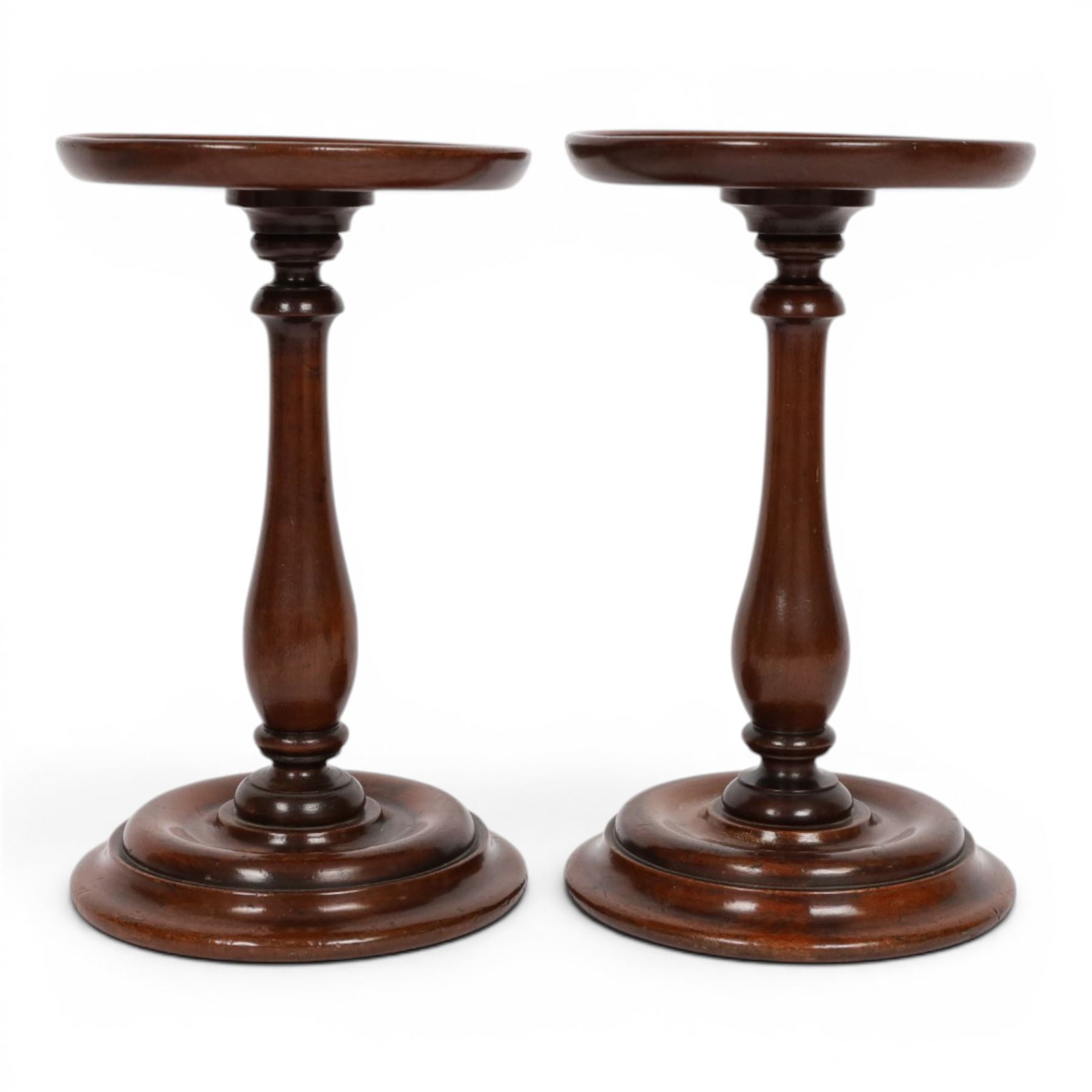Pair of 19th century turned mahogany candle stands, each with circular top upon a baluster stem and circular stepped base, H25.5cm