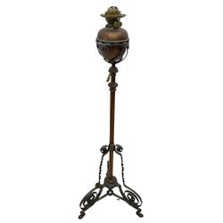 Late 19th to early 20th century wrought metal and copper telescopic oil standard lamp, the lamp and reservoir on scrolled supports with waved band, handle operating telescopic action, tripod base with scrolled terminals and twisted decoration, splayed pad feet 