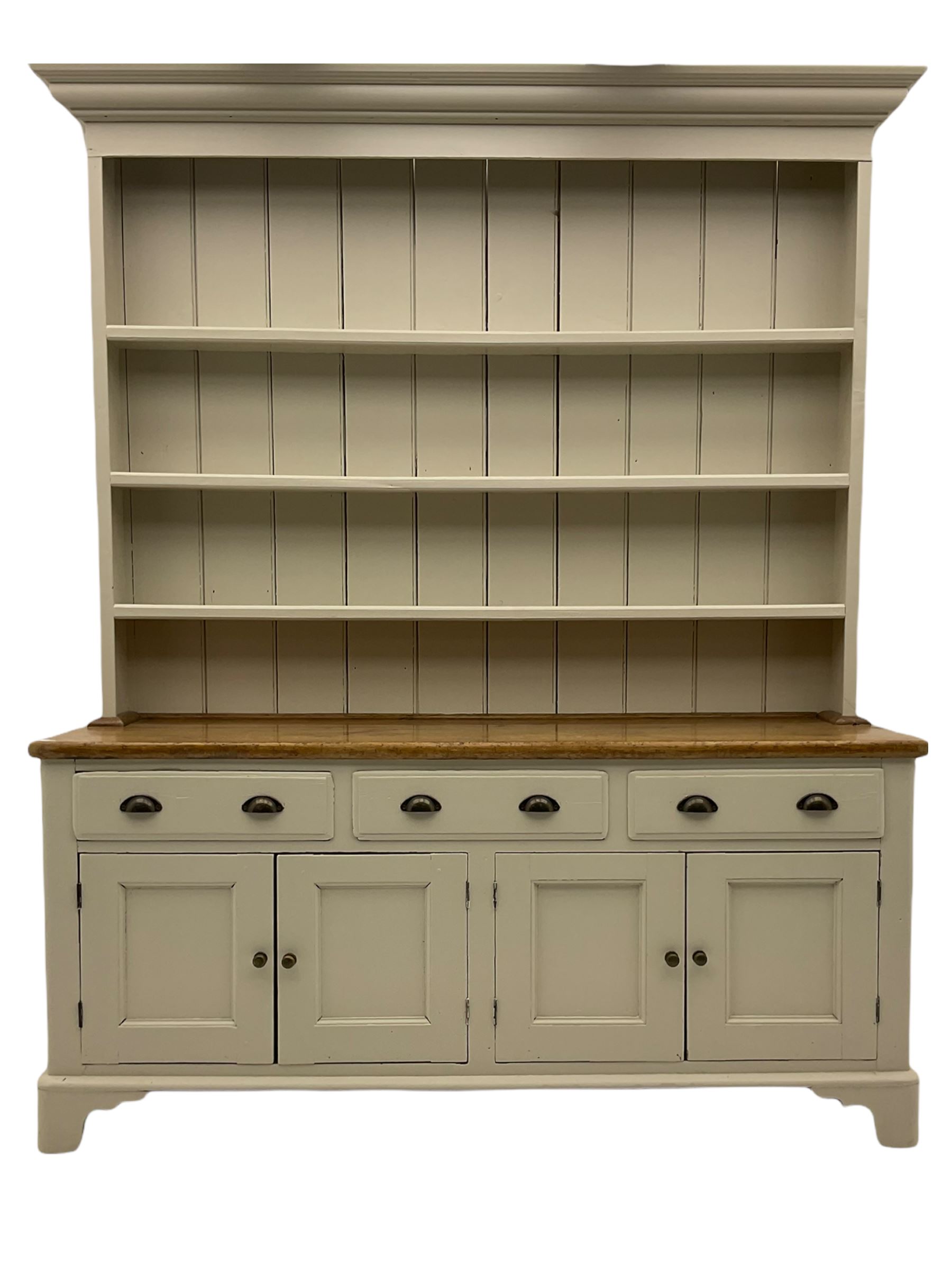 Victorian pine dresser, raised painted three heights plate rack with projecting cornice, waxed top over pained base fitted with three drawers and two double cupboards, bracket feet