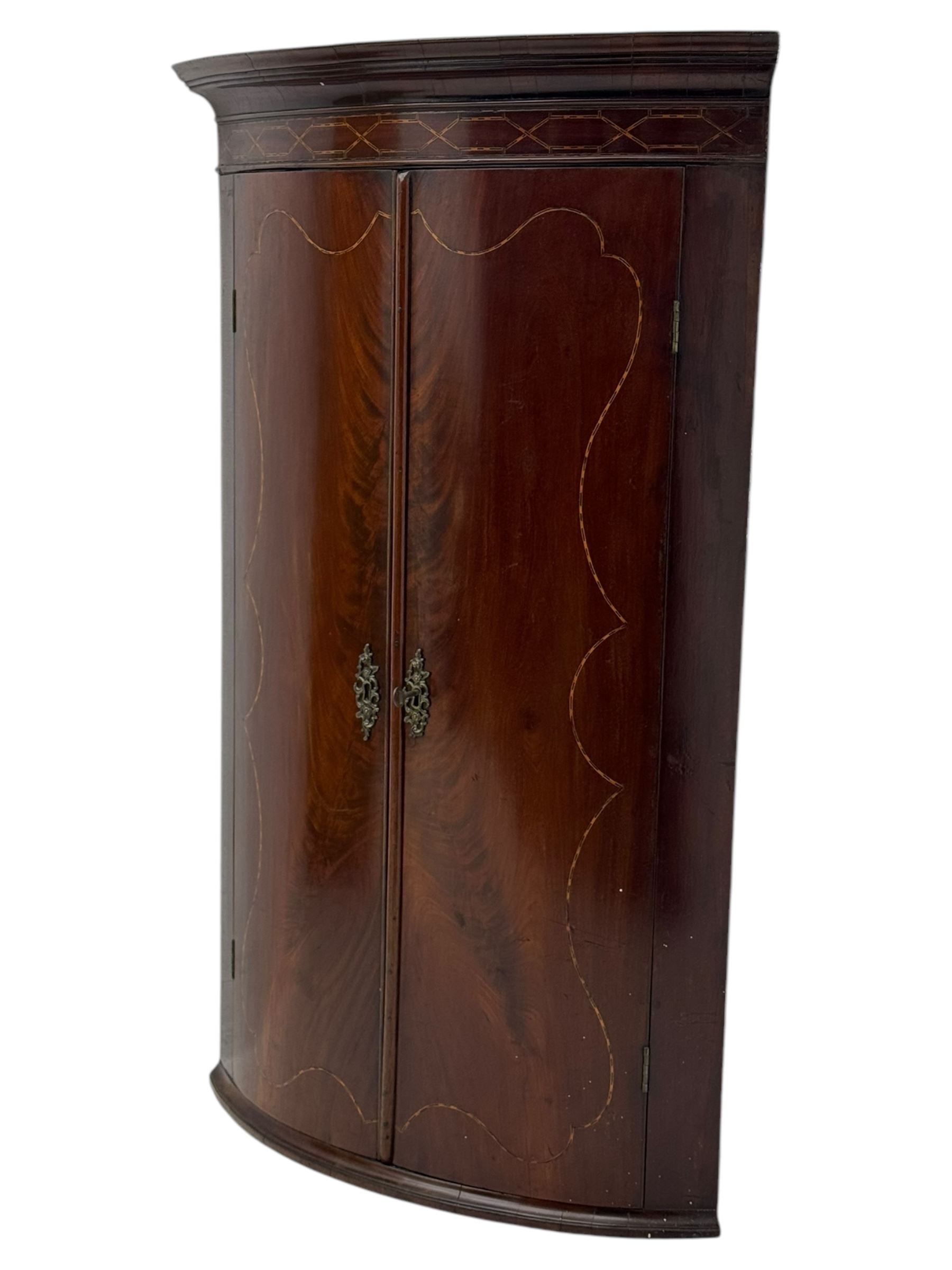 Late Georgian mahogany hanging corner cupboard, moulded cornice with interlaced boxwood stringing pattern above two cupboard doors inlaid with wave form boxwood stringing and four internal shelves 