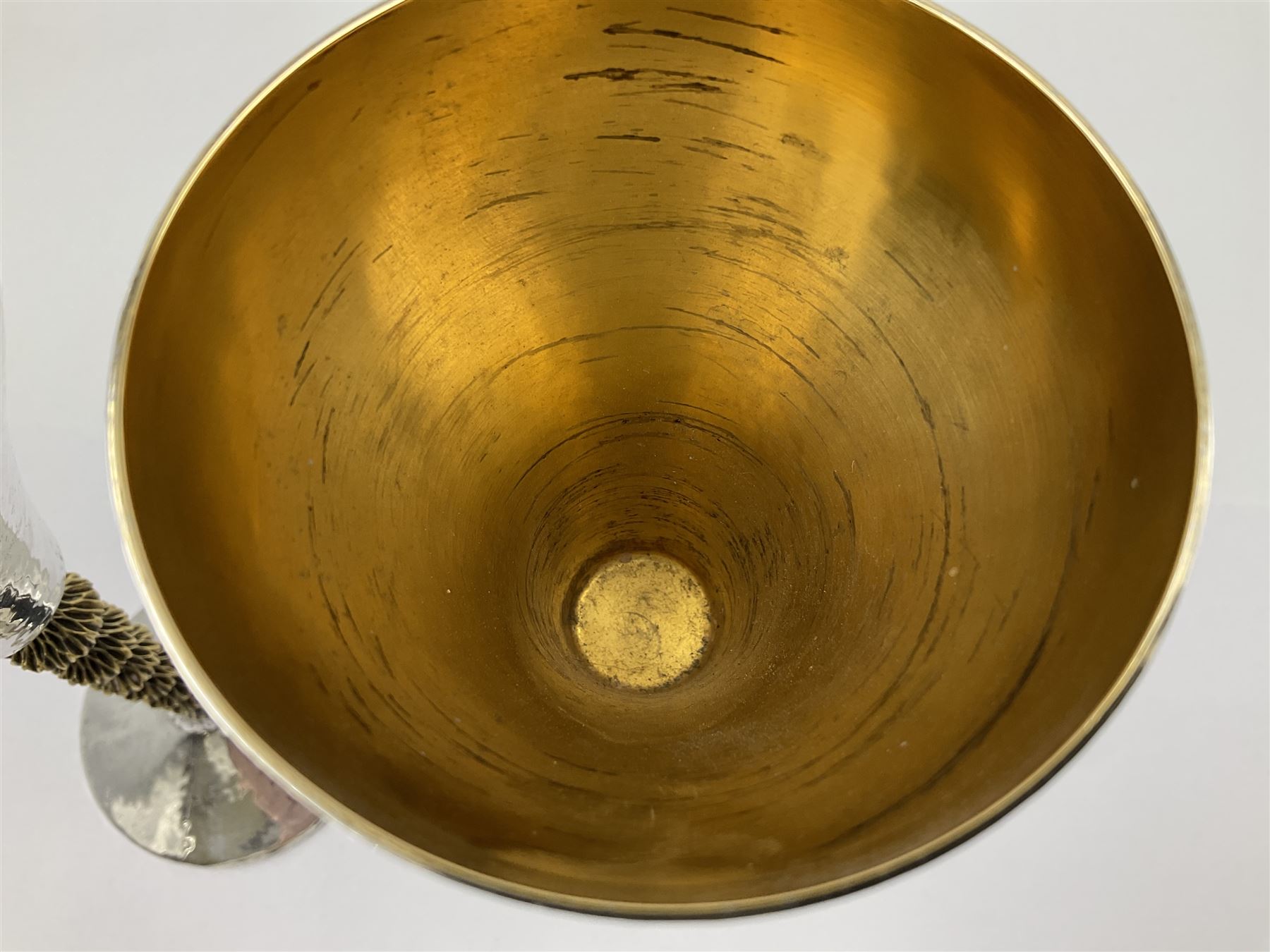Pair of modern silver goblets by Stuart Devlin, the tapering cylindrical bowls each with spot hammered decoration and gilt interiors, the parcel gilt stems with signature textured detailing and six graduating knops, upon conforming spreading circular foot, hallmarked Stuart Devlin, London 1976, H17.7cm