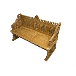 Carved teak garden bench, the cresting rail carved and pierced with foliate design, shaped arms and end supports decorated with scrolling foliage and flower heads