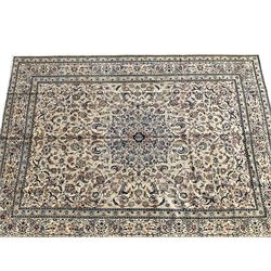 Persian Nain ivory ground carpet, the central rosette medallion surrounded by all over trailing indigo scrolling and foliate decoration with palmettes, the guarded border decorated with repeating Shah Abassi motifs, with stylised flower heads within the bands