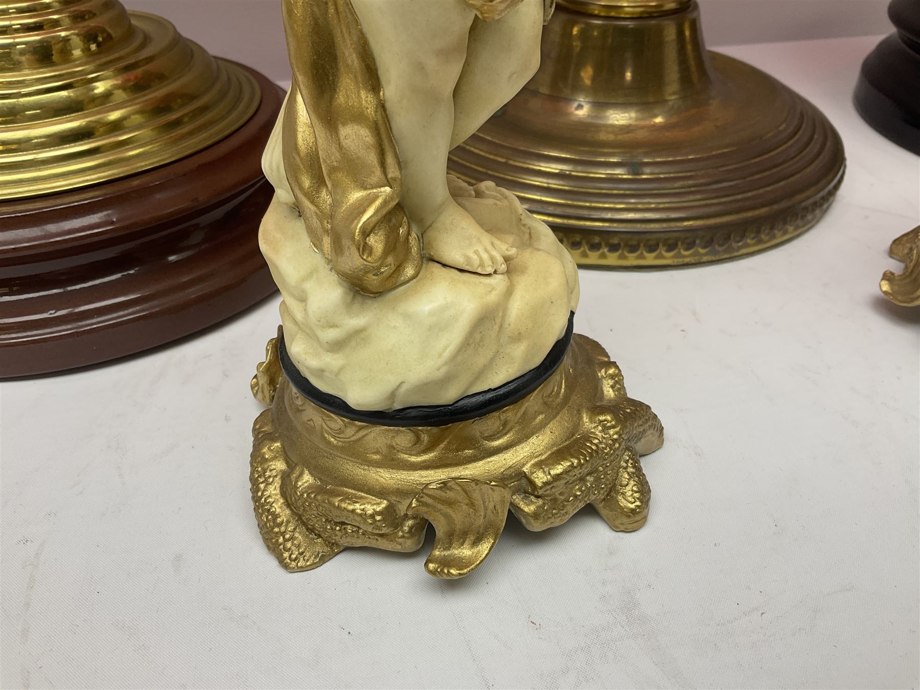 Victorian cast brass oil lamp, with fluted pink glass shade, together with two smaller brass oil lamps with pink shades and reservoirs and a pair of oil lamps, the bases modelled as putti, with pink glass reservoir  and frosted shades, tallest H70cm