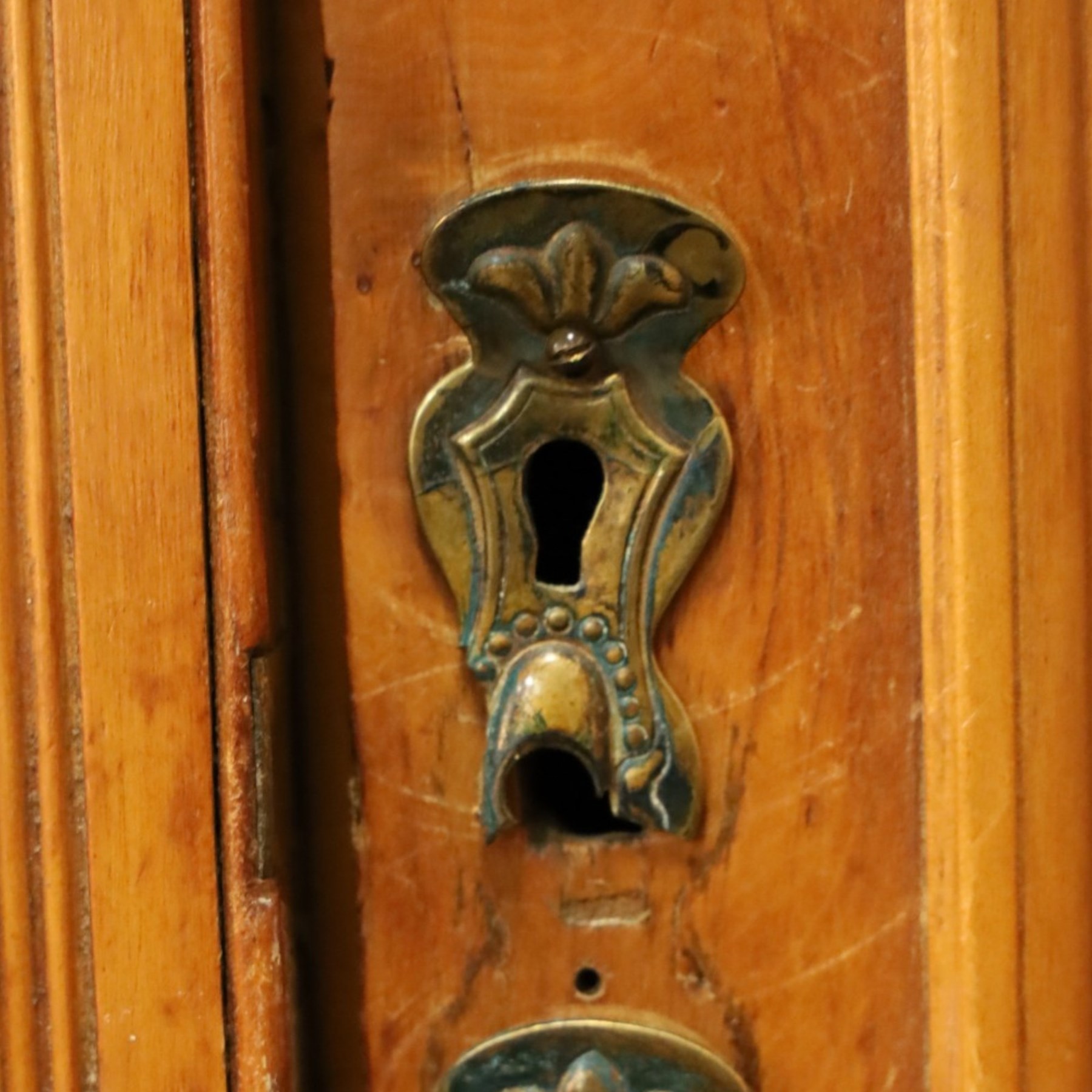 Edwardian walnut triple combination wardrobe, projecting pediment with pierced foliate scroll cresting above a central cupboard flanked by bevelled mirrored doors, over open recess with mirrored back, above two short and three long drawers with brass handles, interior fitted with hanging rails and shelf, raised on plinth base