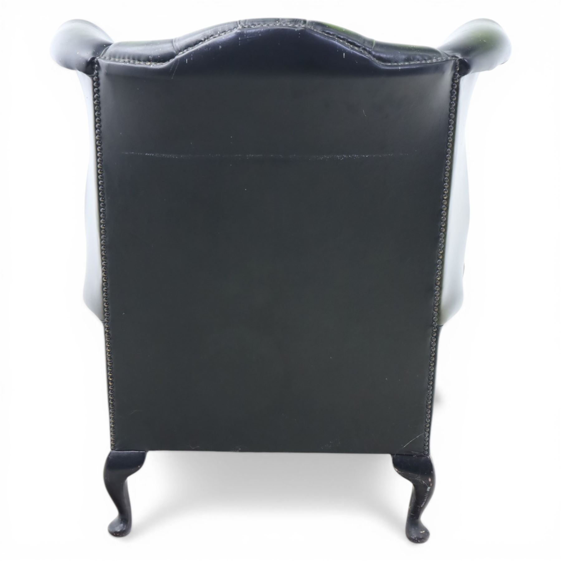 Late 20th century green leather chesterfield style wingback armchair, with deep buttoned back, scrolled wings and arms with studded borders, loose seat cushion, raised on cabriole legs