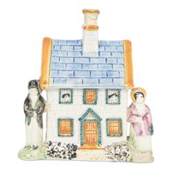 19th Century Staffordshire pearlware Prattware type money box, modelled as a houe with two figures to the front corners, H13cm