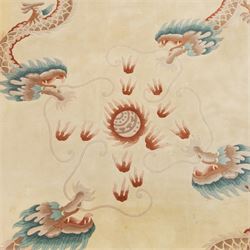 Late 20th century Chinese wool carpet, cream field with five stylized dragons arranged in a circular formation around a central flaming pearl motif, dragons depicted with elongated bodies and clawed feet amongst stylized cloud forms, enclosed within a narrow inner border and a wider outer border decorated with traditional Chinese motifs and symbols