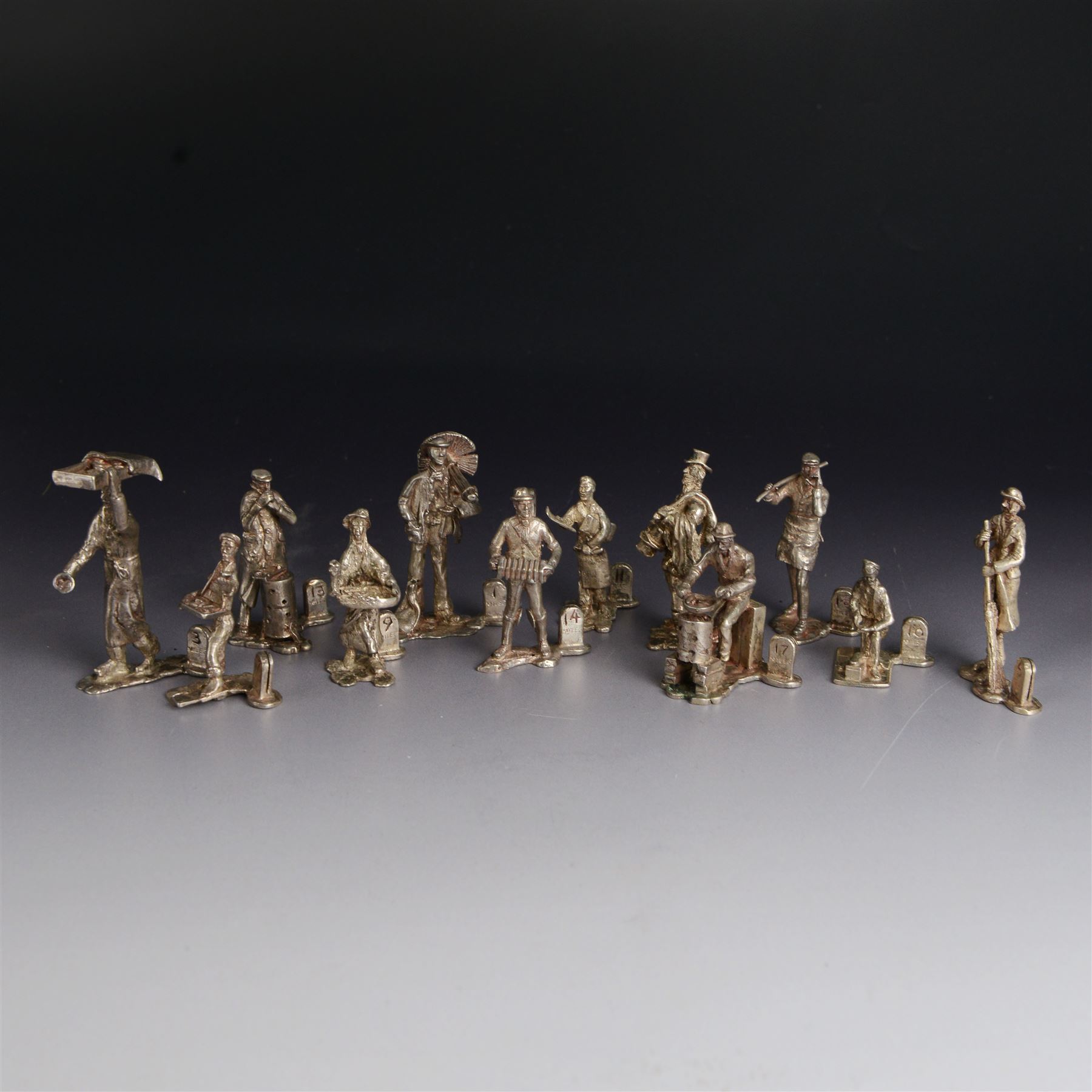 Set of twelve silver place card holders from the 'Cries of London' series, each depicting traditional London street traders, hallmarked Thomas Charles Jarvis, London 1975, tallest H6.5cm