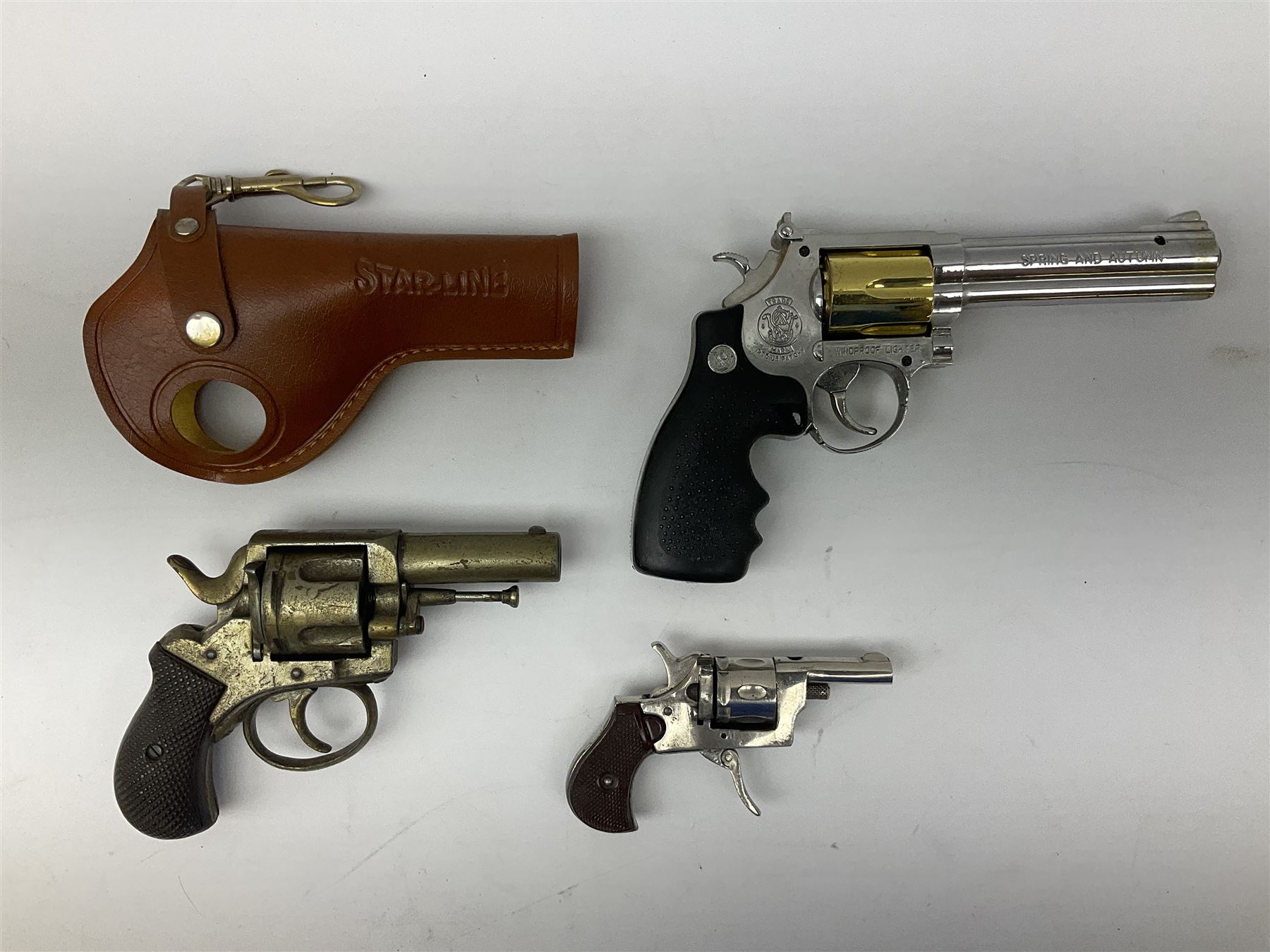 Early 20th century Flobert 5mm blank firing revolver with six-shot chamber, top venting, nickel plated with folding trigger No.118 L12.5cm overall; replica non-firing 'British Bulldog' revolver; and Windproof gas lighter inscribed 'Revolver-99 Spring and Autumn' in holster marked 'Star-Line'