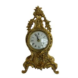 20th century gilt metal timepiece mantle clock with a Quartz movement,
case in a decorative baroque style with a white enamel dial with Roman numerals and pierced steel hands.
