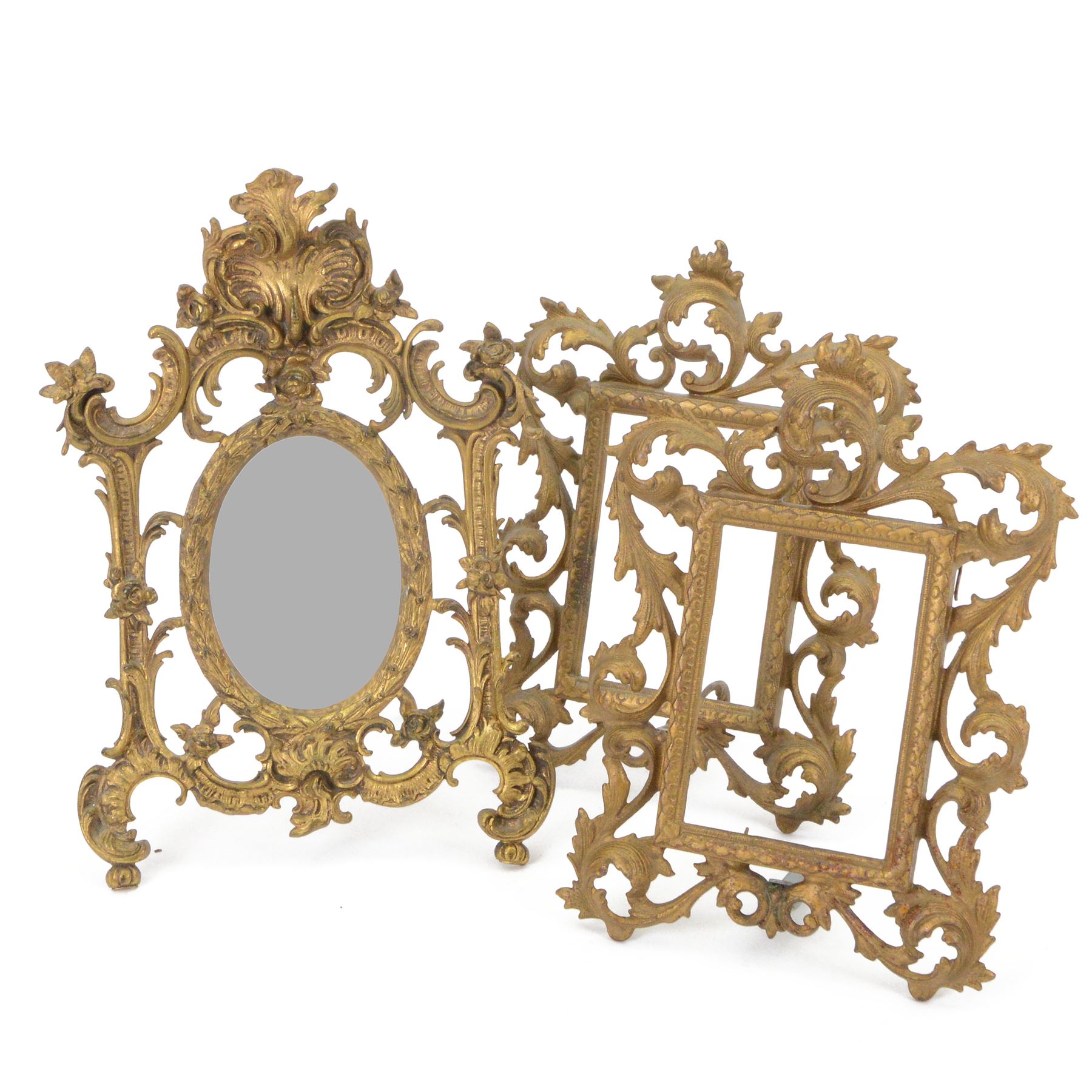 Rococo style cast gilt metal table mirror, the oval mirror plate within an open C scroll and foliate detailed frame, with easel style support verso, H33cm, together with a pair of cast gilt metal acanthus surround frames, H28.5cm
