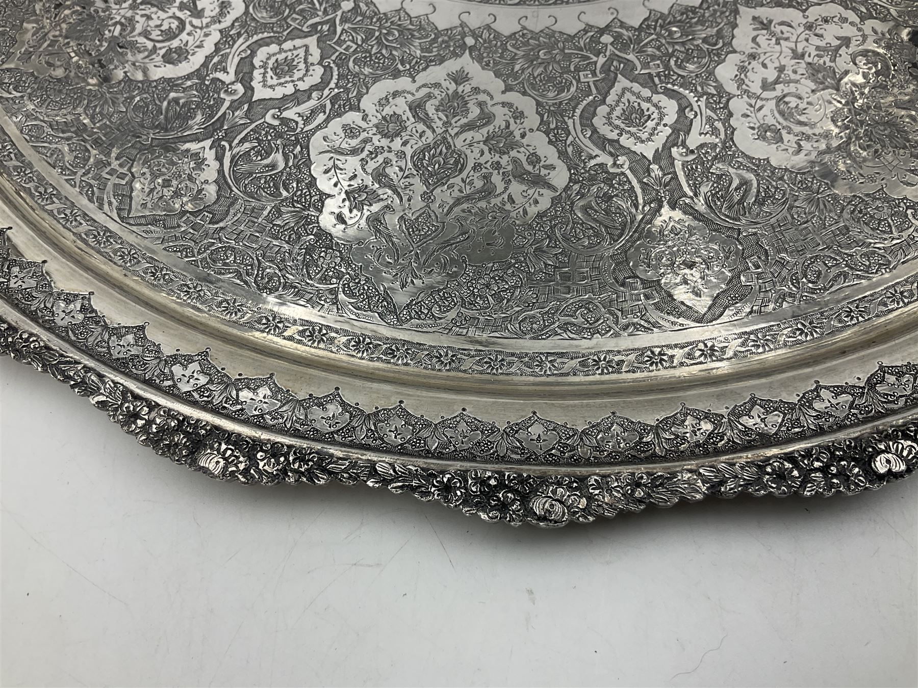 Early/mid 20th century Persian silver tea service, comprising circular serving tray, teapot, twin handled sucrier and cover, milk jug, five tea glasses with six silver holders, six tea spoons, and pair of sugar tongs, each profusely chased with foliate arabesque decoration, each bearing marks including 84 for 840 fineness, tray D40cm, teapot H16cm