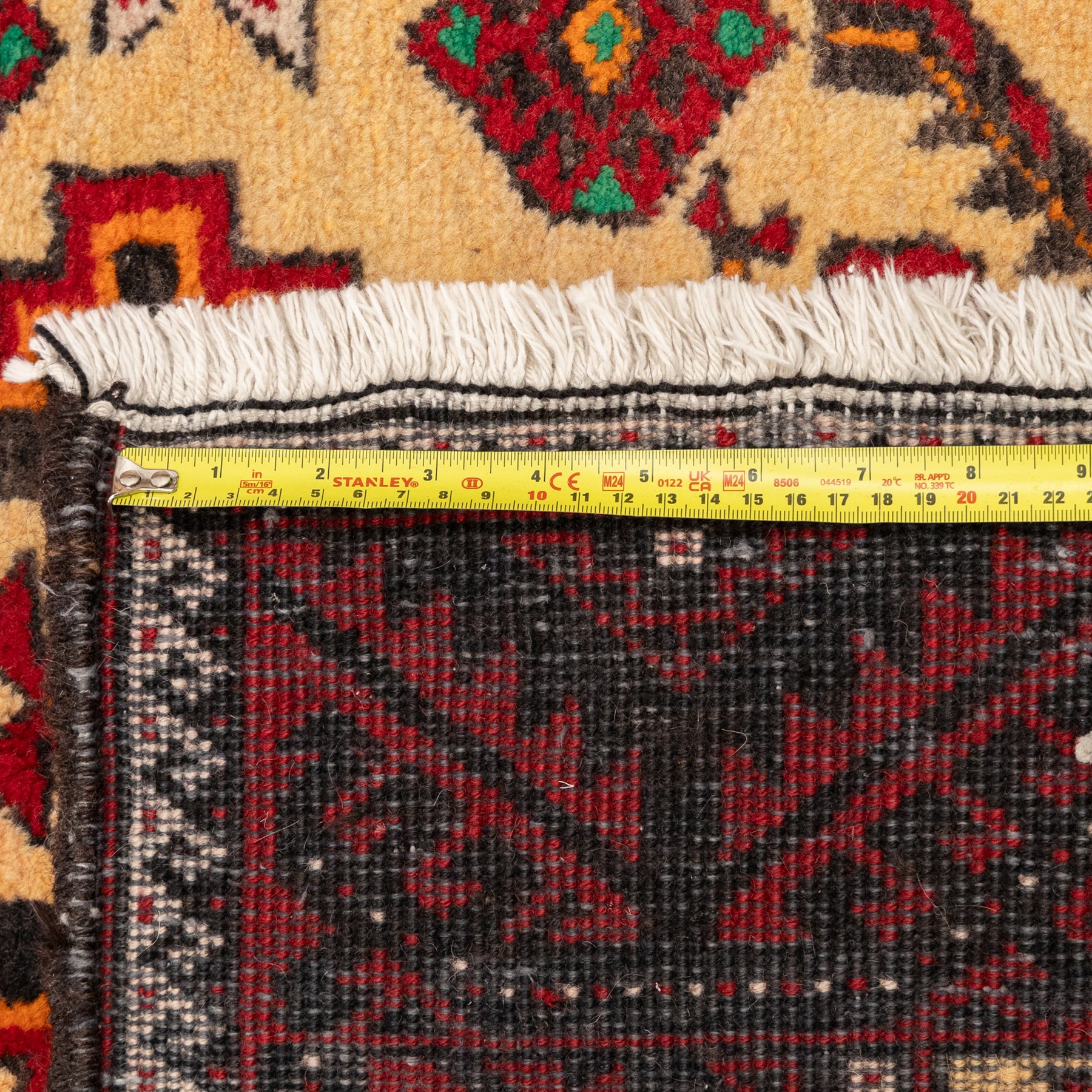 North East Persian Meshed Baluch rug, the ivory field decorated with two stepped diamond medallions and angular red motifs, interspersed with stylised horned animals, birds, flowerheads and geometric devices, enclosed by a dark brown border of repeating red serrated leaves and narrow ivory guard bands