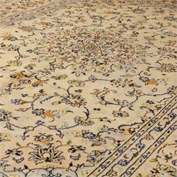 Central Persian Kashan hand-knotted carpet, ivory ground with central rosette medallion surrounded by scrolling floral vines and palmettes, field framed by a meander border flanked by multiple guard stripes, with cotton fringe end and a replaced fringe end