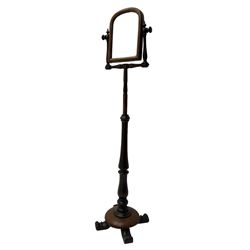 Early Victorian mahogany shaving mirror, arched frame with plain mirror plate on turned horns and supports, adjustable height mechanism on turned stem, circular platform base with four extending block feet carved with scrolled foliage 
