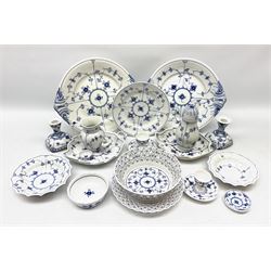 A collection of assorted Royal Copenhagen blue fluted lace tablewares comprising a pierced fruit basket, sugar sifter, pair of candlesticks, reticulated plate, two leaf shaped serving dishes, salt cellar, two egg cups, pepper pot, two large twin handled plates, together with other Royal Copenhagen porcelain (19)