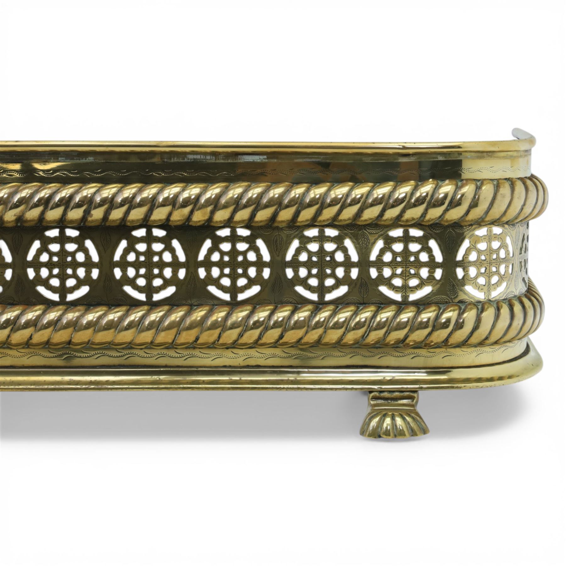 20th century pierced brass fender, with pierced roundels between oblique gadrooned borders, upon three paw feet