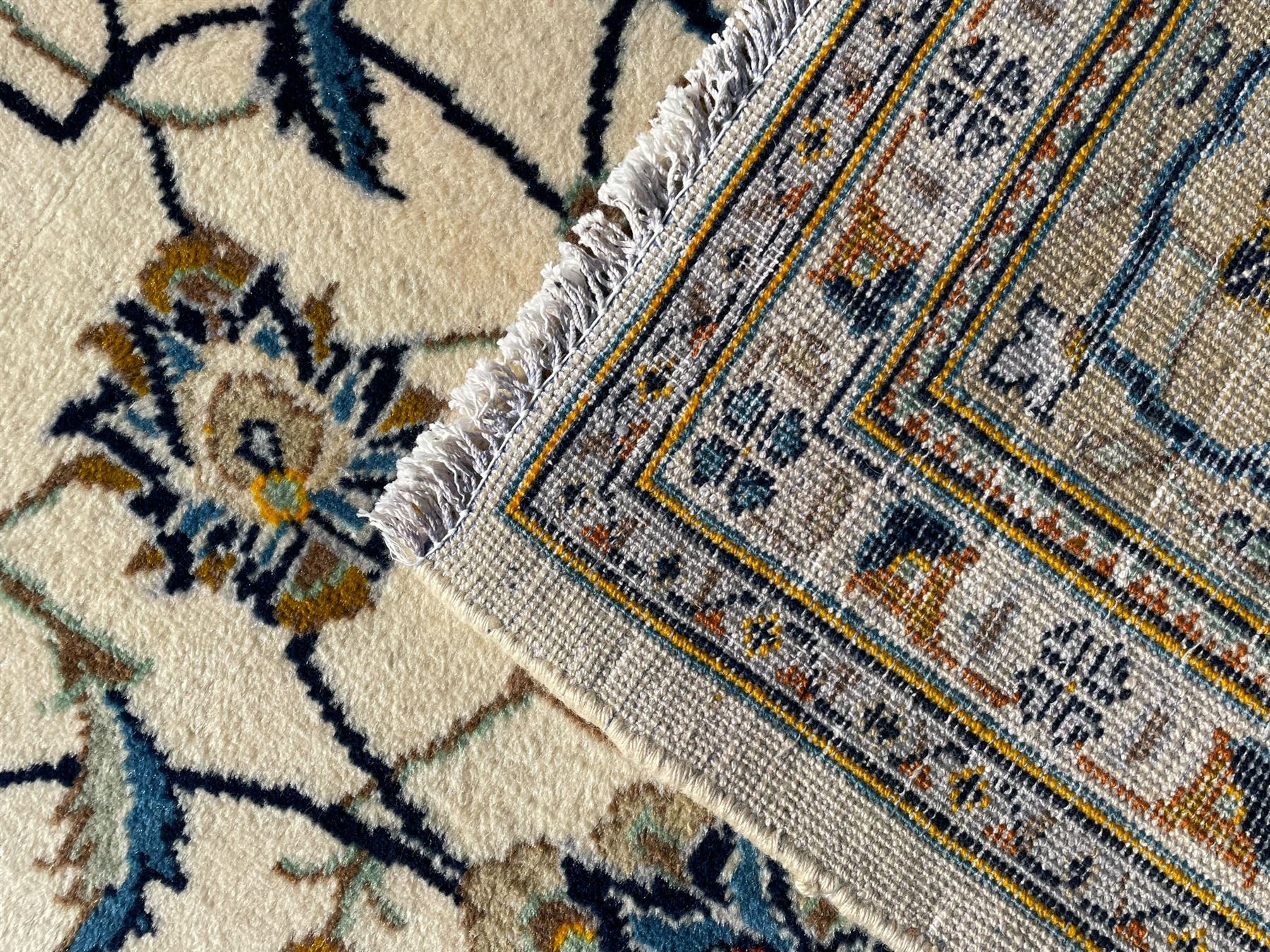 Persian Kashan ivory ground carpet, overall floral design, the field decorated with scrolling and interlaced leafy branches interspersed with palmettes, scrolling border decorated with stylised plant motifs, within floral pattern guard stripes 