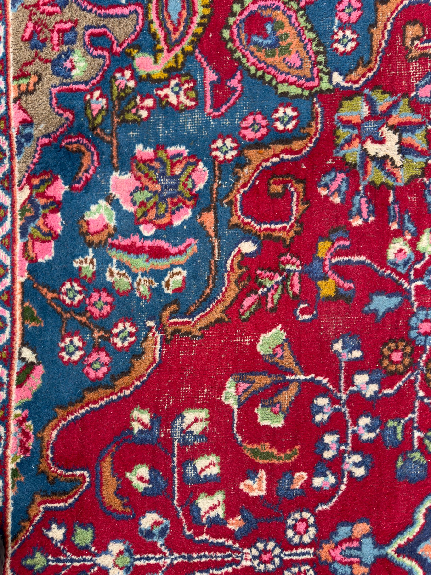 Pair of Persian wool rugs, each with rich red ground, one centred with a diamond-shaped medallion and navy spandrels within a floral field, the other with radiating floral medallion and scrolling foliate motifs, both enclosed by multiple borders with palmette and flowerhead designs, from the region of Kashan 291x376, 299 x 378 