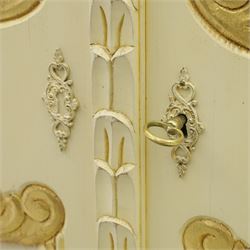 20th century French white and parcel gilt painted armoire, the shaped and scroll moulded cornice centred with a stylised foliate, the double doors with raised panel reserves applied with gilt foliate scrollwork, flanked by fluted pilasters with floral capitals, opening to a fitted interior with shelving and hanging space, raised on a moulded plinth on squat bun feet