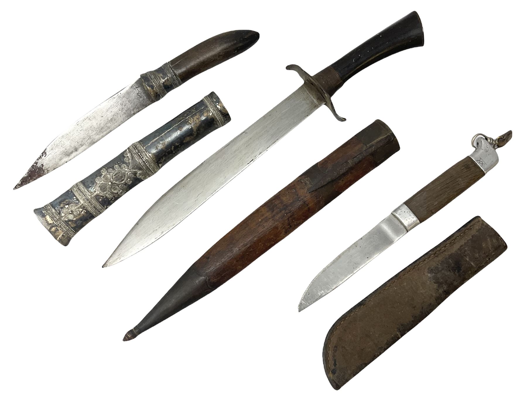 Burmese dha dagger with 15cm steel blade, white metal ferrule and horn handle, in white metal and filigree scabbard L30.5cm; a Burmese long bladed knife with horn handle and brass mounted teak scabbard; and another Eastern dagger in sheath (3)